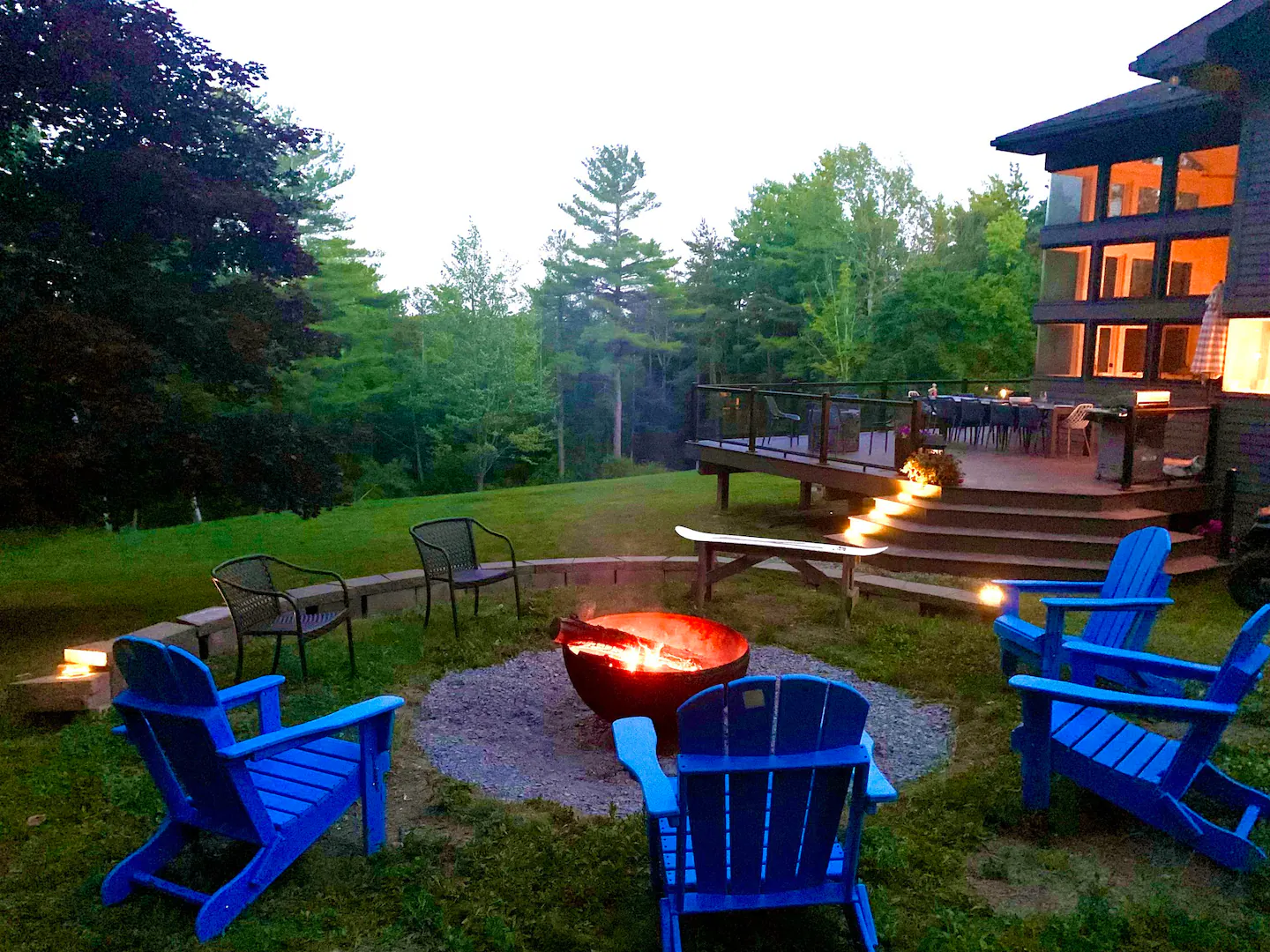 Two firepits and blue Adirondack chairs behind Canandaigua Retreat